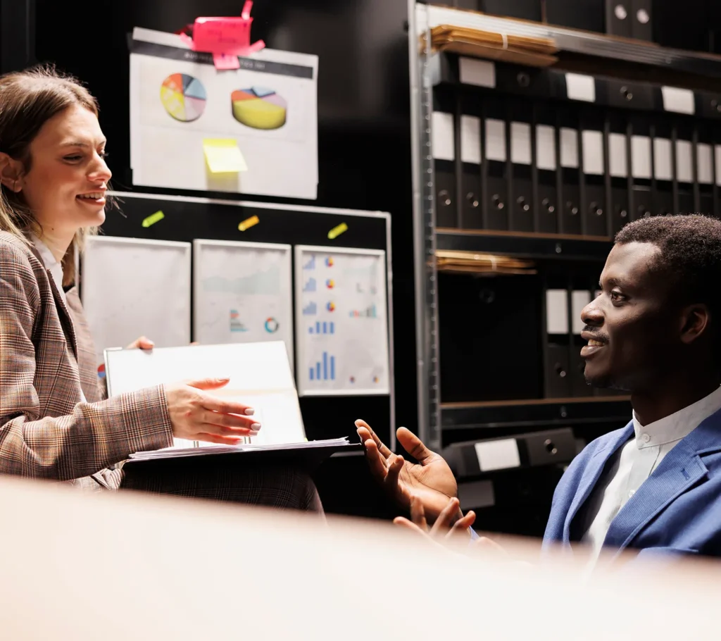 Two tax professionals with ledger books in a records room