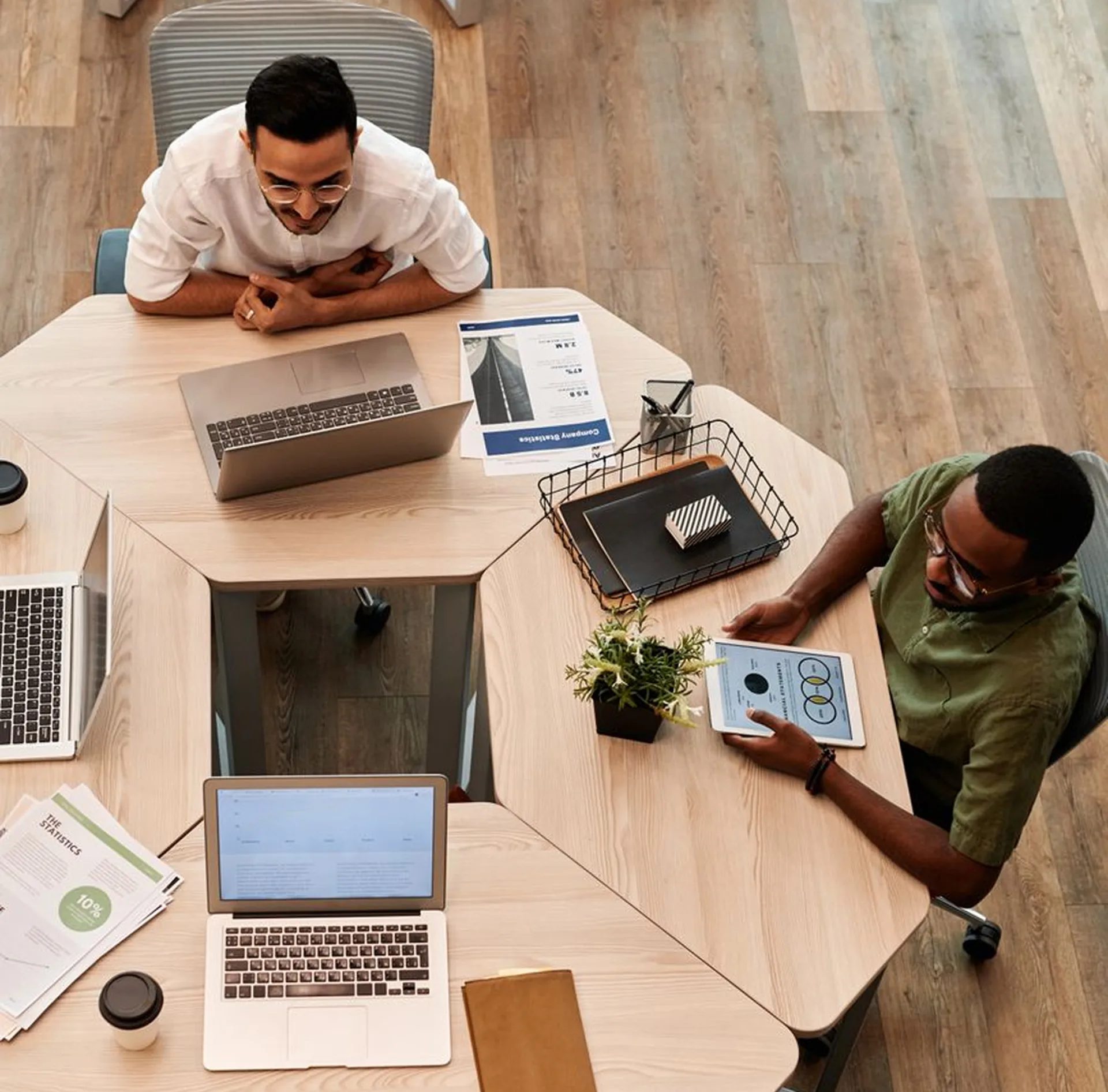 Team meeting around a hexagonal table with laptops