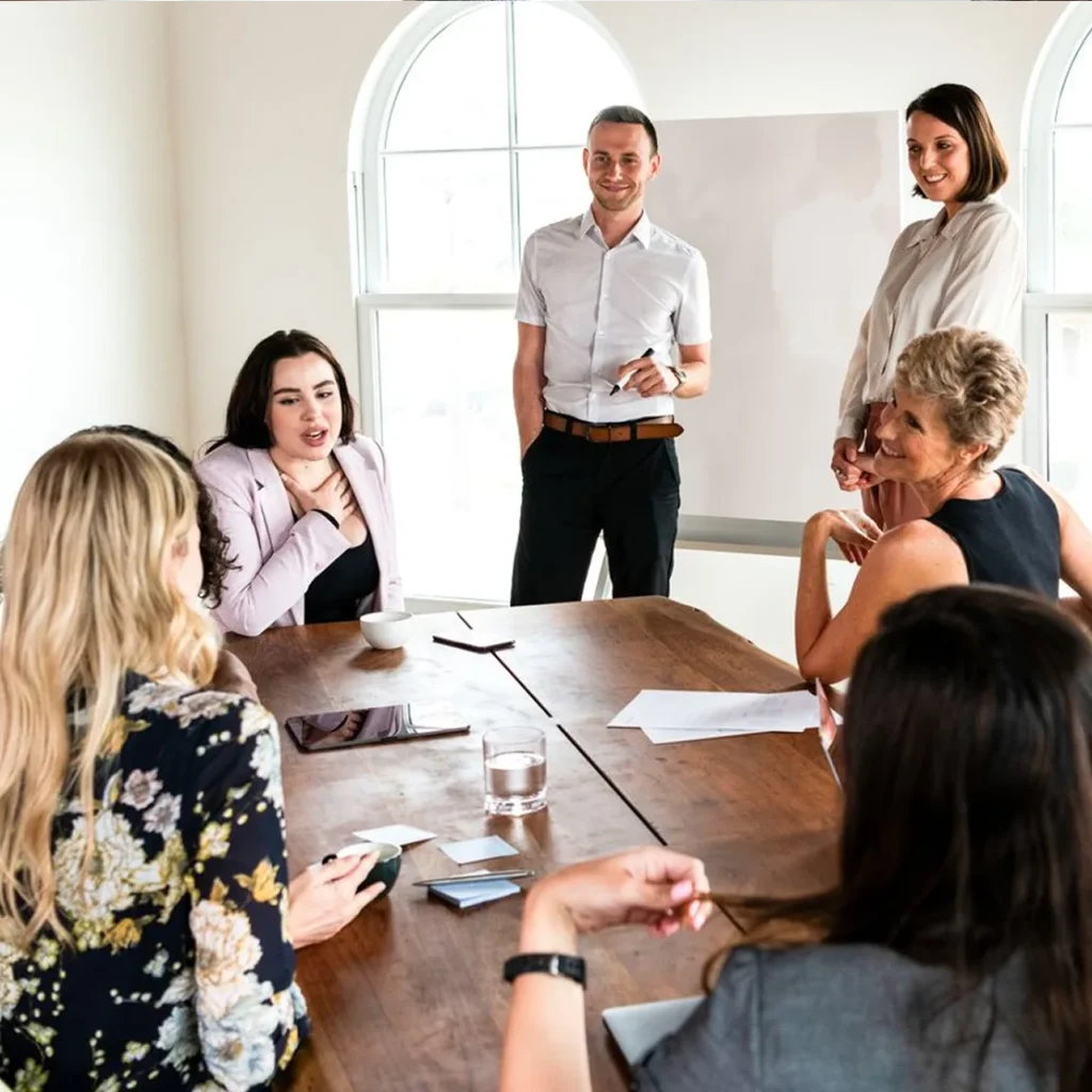 Business team planning around a conference table, whiteboard behind them